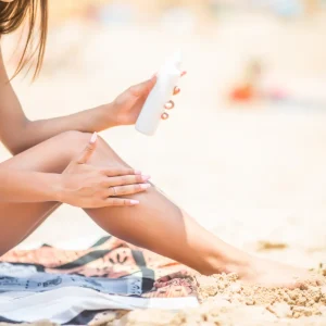 sunscreen-suntan-lotion-in-spray-bottle-young-woman-in-spraying-tanning-oil-on-her-leg-from-bottle-lady-is-massaging-sunscreen-lotion-while-sunbathing-at-